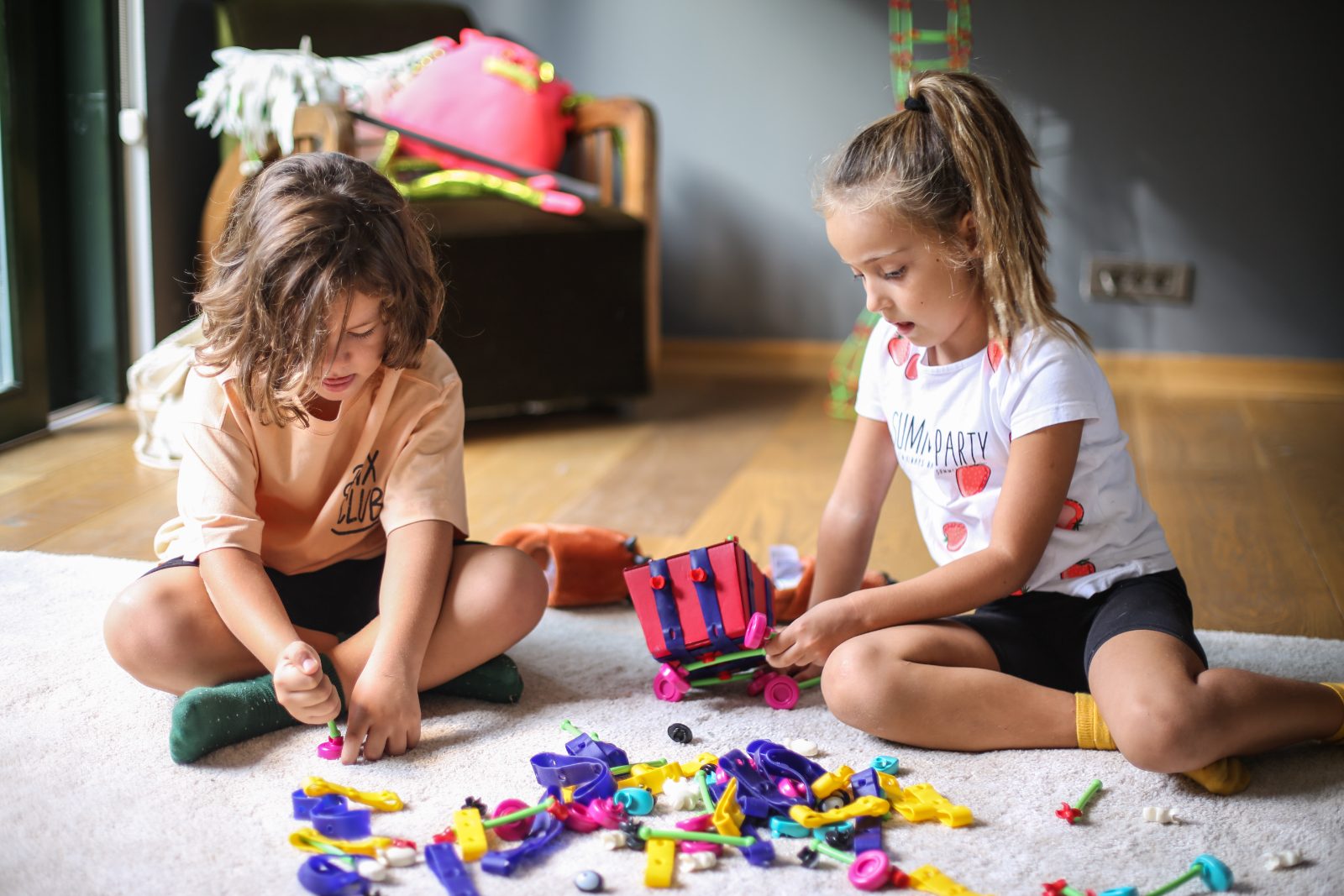 Two children sorting Toyi pieces on the floor