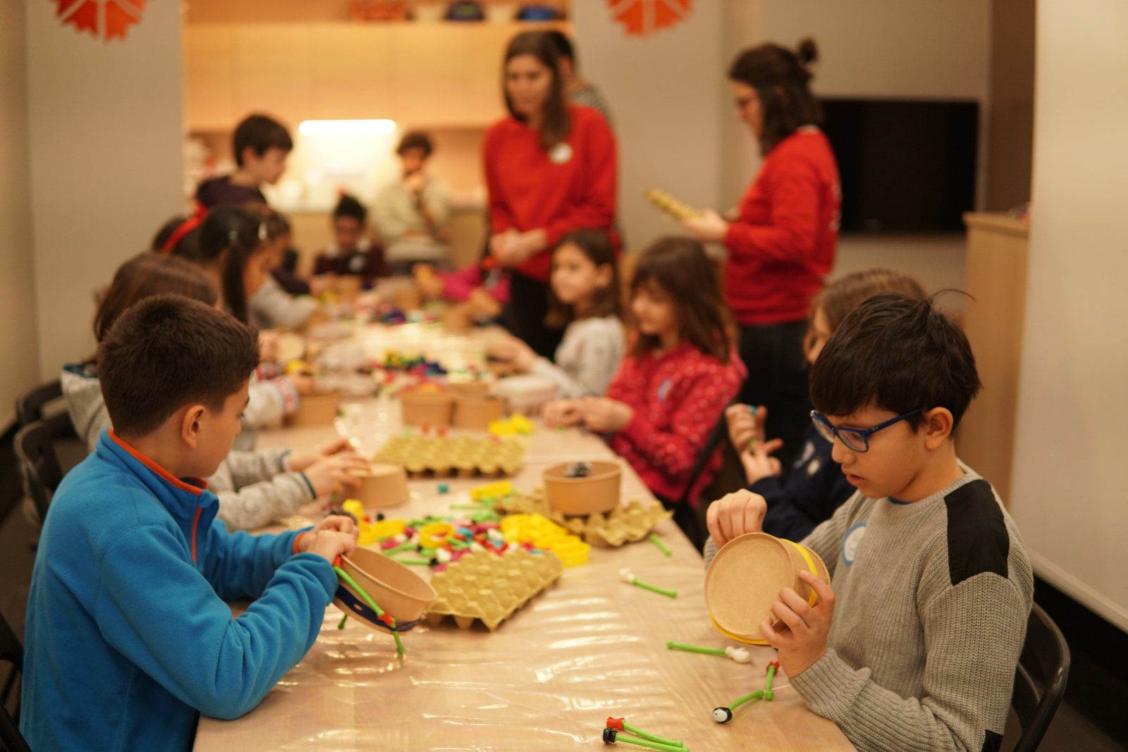 A class of children building toys around a long table at a Toyi workshop